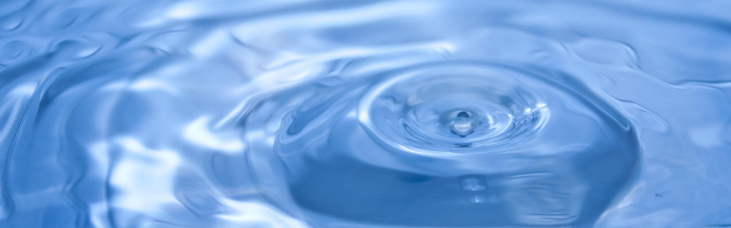 Een druppel water valt in een grote plas.