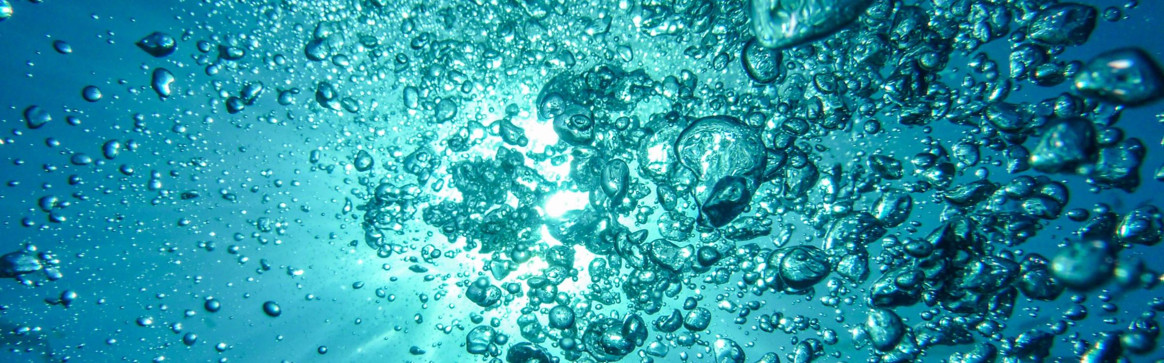 De zee waar de zon doorkomt, er zijn veel bubbels aanwezig door boten.