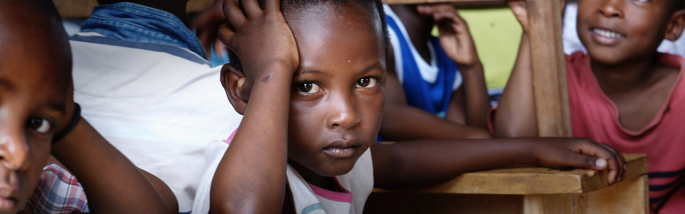 Kindjes uit Afrika zitten op oude schoolbanken de les te volgen.