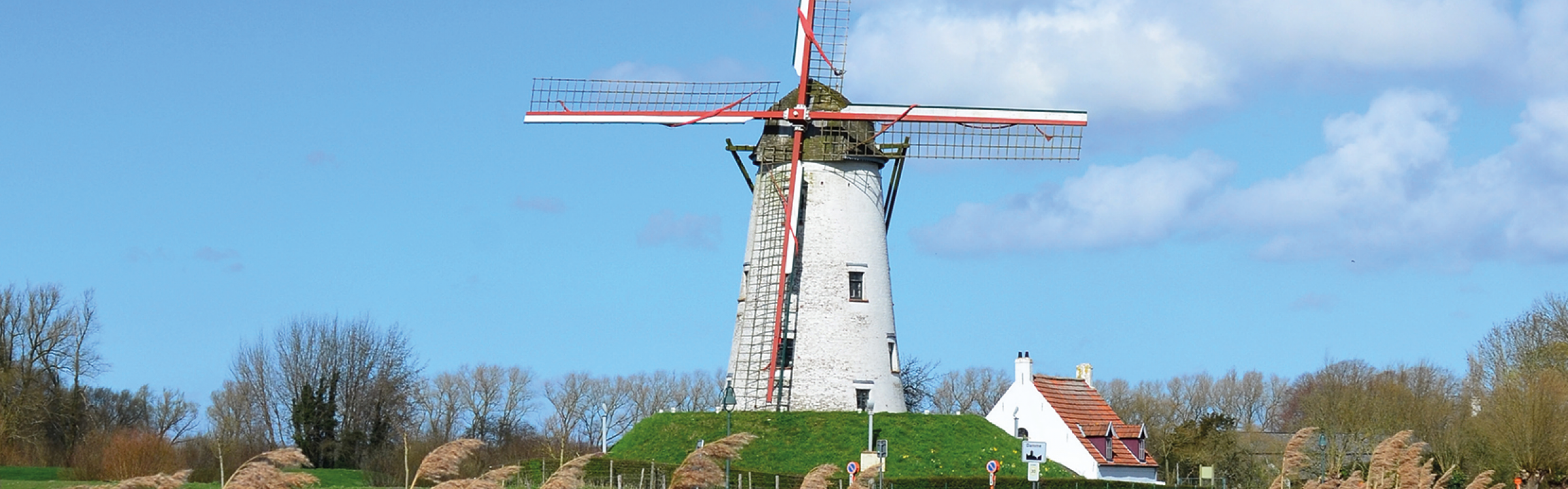 Een oude windmolen aan het draaien langs de rivier op een zonnige dag.