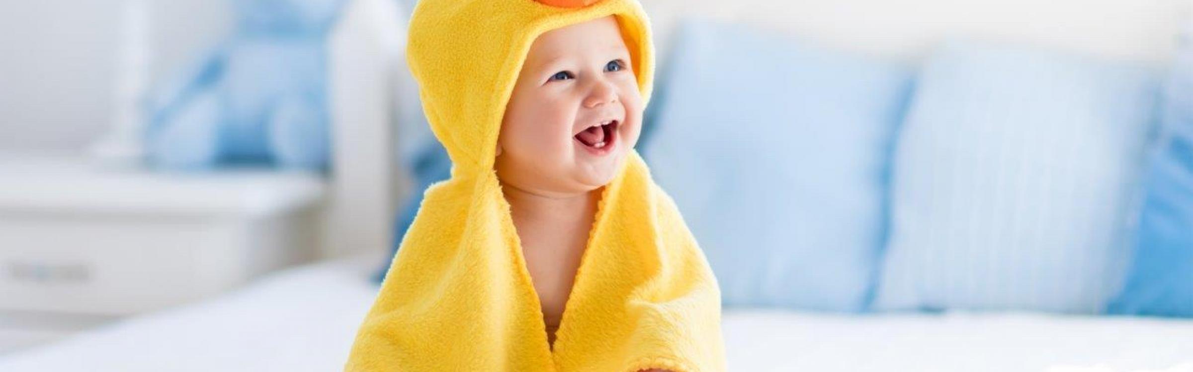 Een kindje is aan het lachen met zijn onesie aan.