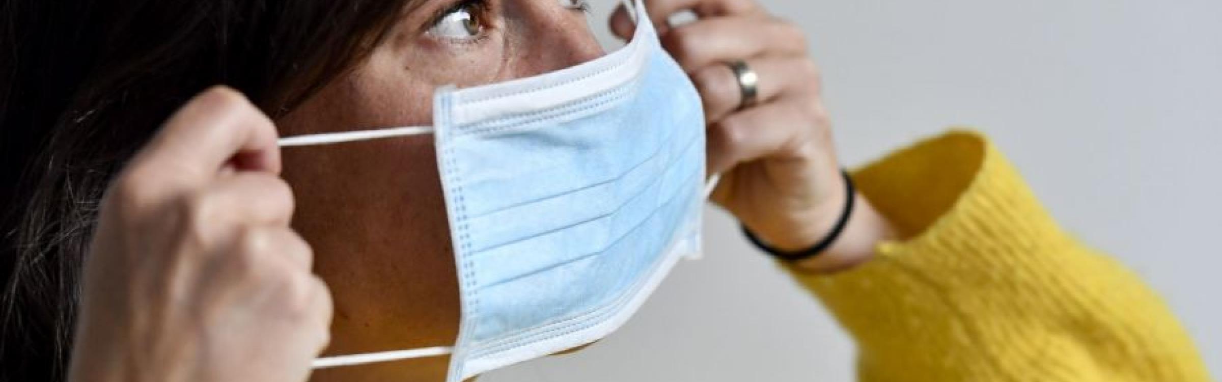Een vrouw doet haar mondmasker aan ter bescherming tegen het coronavirus.