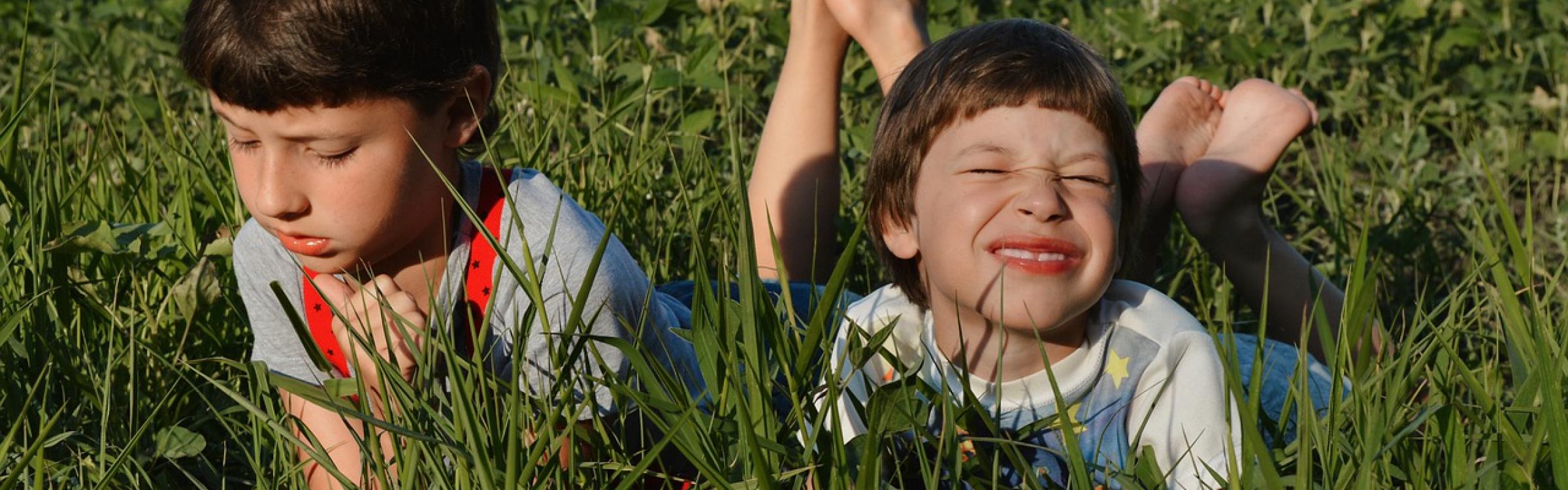 Twee kindjes genieten van het zonnetje in het gras.
