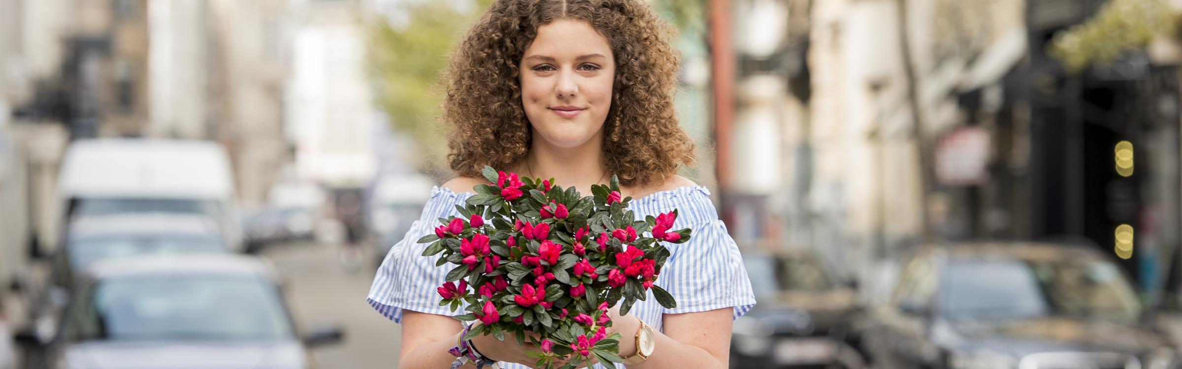 Een vrouw koop een azalea voor Kom Op Tegen Kanker.
