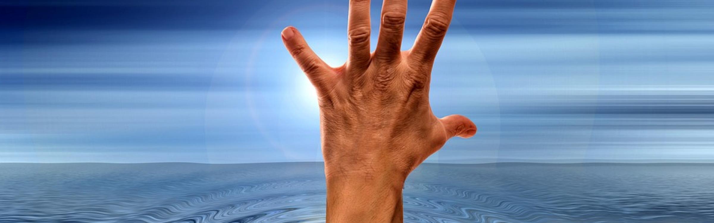 Iemand steekt zijn hand uit boven water om niet te verdrinken en hulp te vragen.