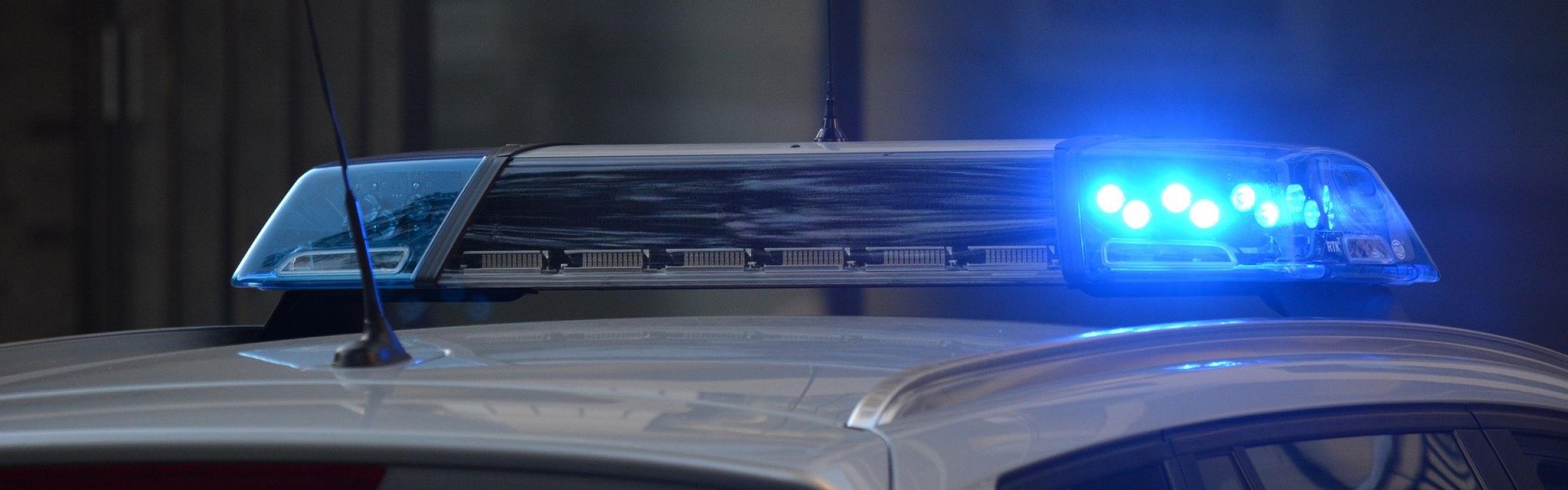 Een politiewagen rijdt met zijn zwaailichten aan.