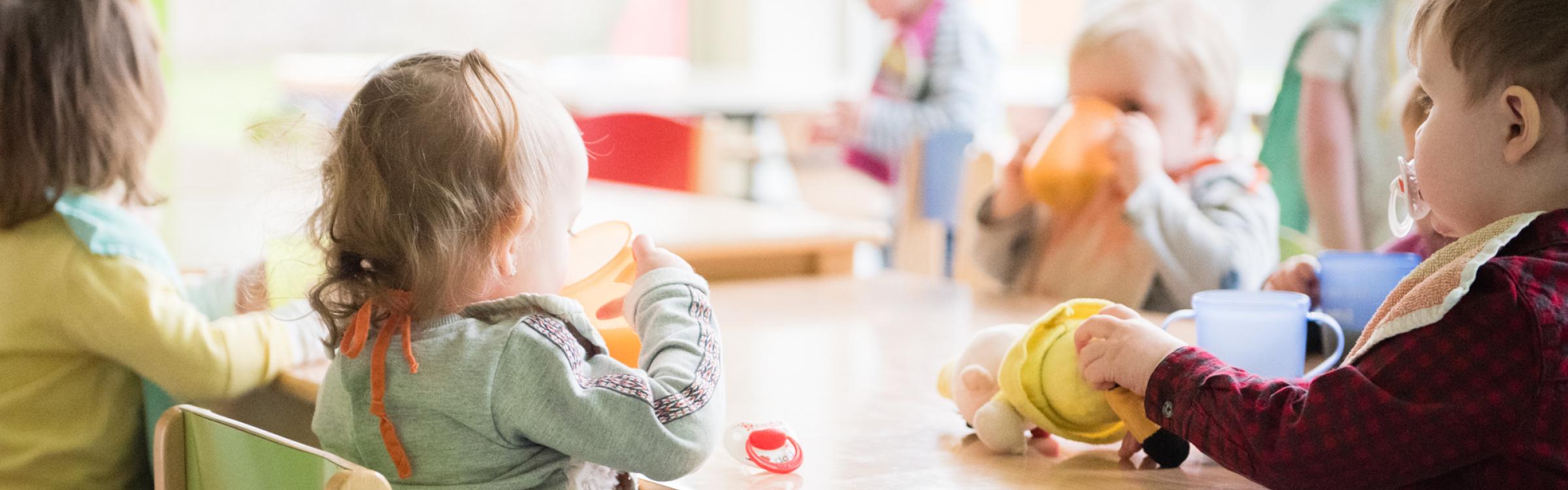 Kindjes zijn aan het eten en drinken in het kinderdagverblijf.
