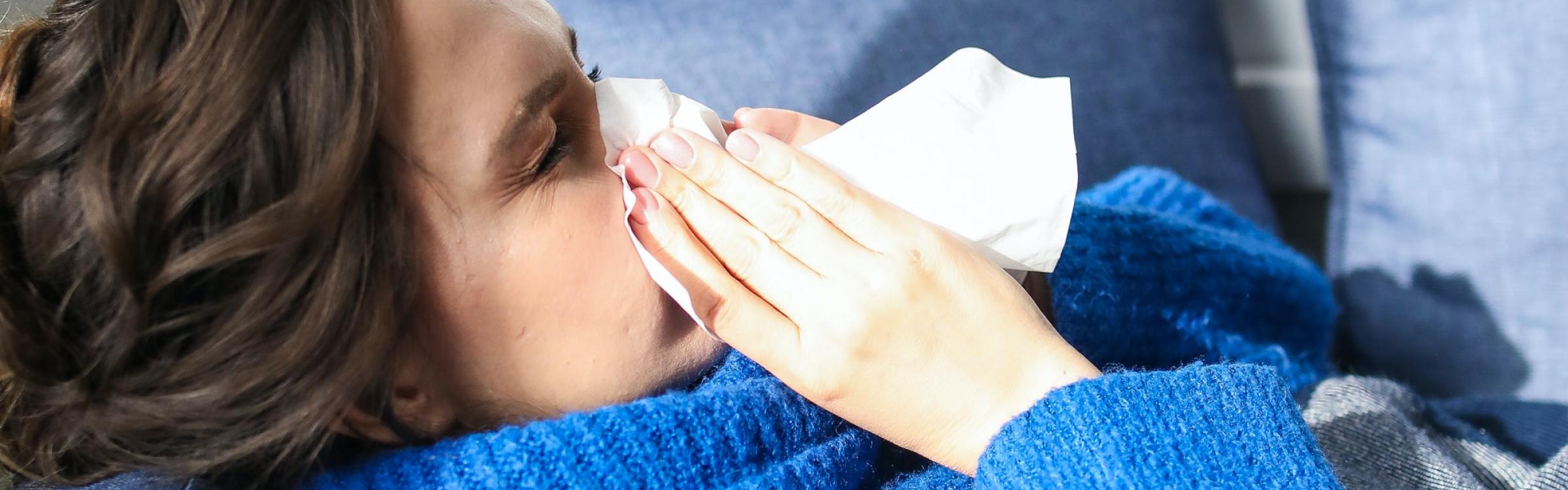 Een vrouw is verkouden en snuit haar neus .