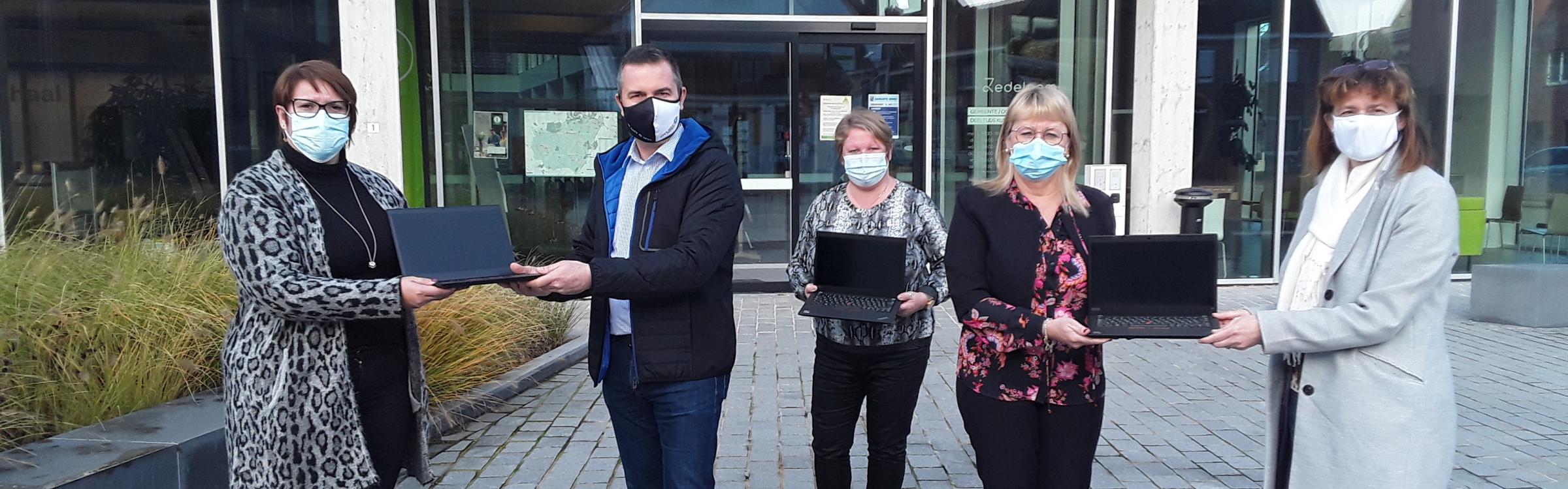 Het lokale bestuur samen met de laptops die ze schenken aan kinderen uit kwetsbare gezinnen.