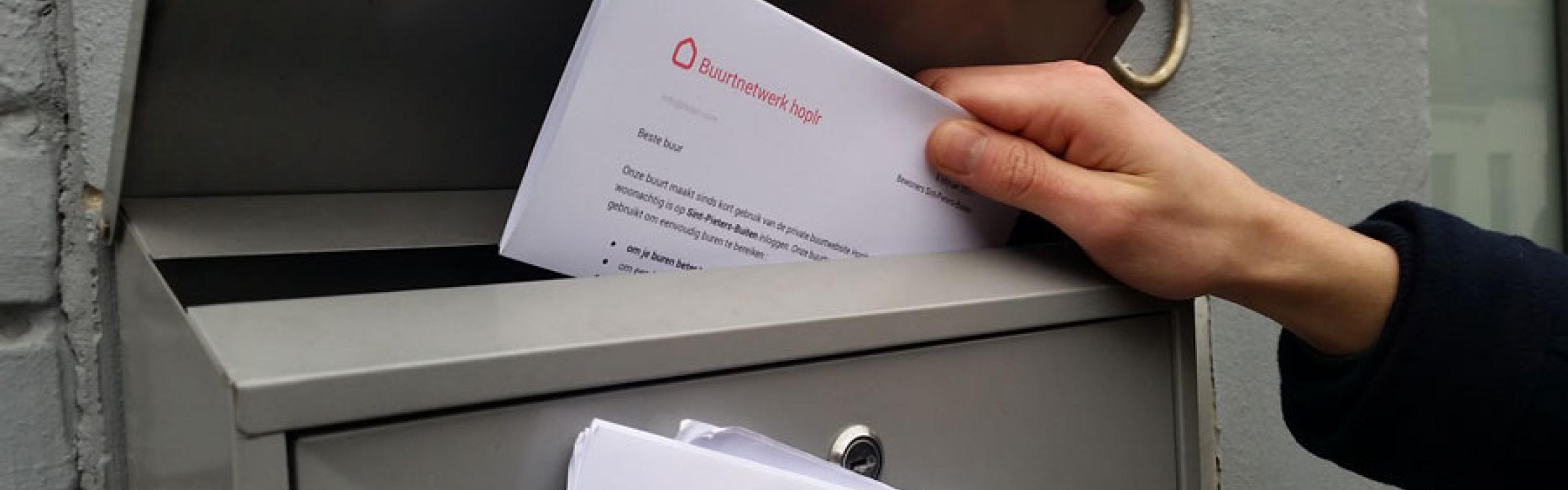 Een persoon steekt een brief in de brievenbus.