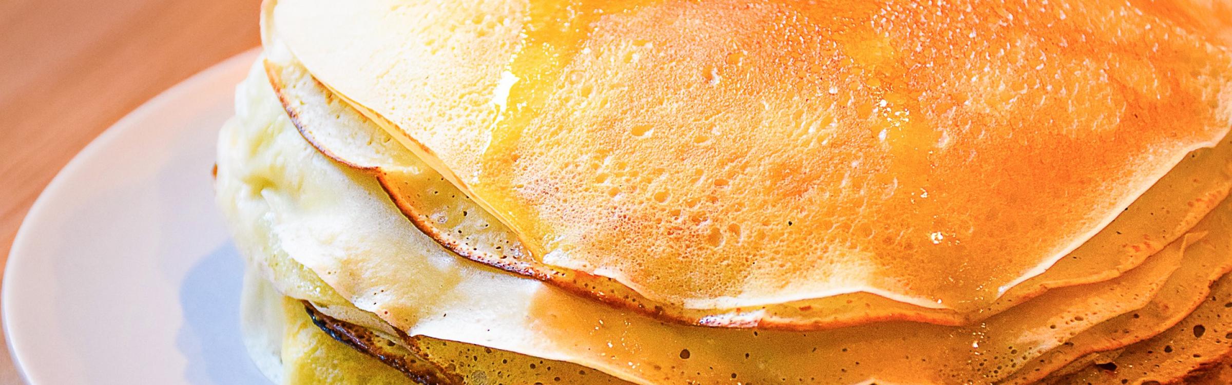 Een stapel pannenkoeken liggen versgebakken op een bordje.