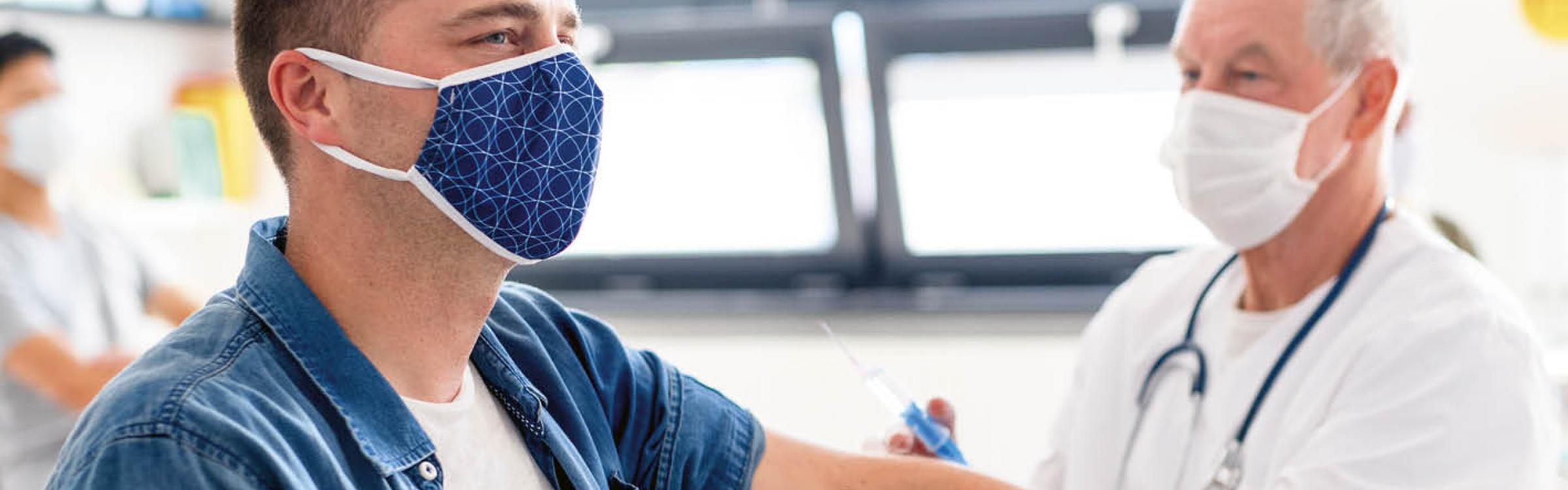 Een verpleger dient iemand een vaccinatie toe.