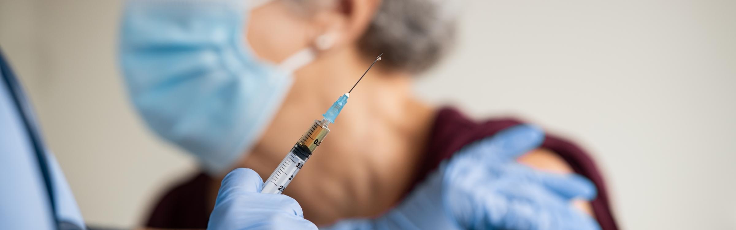 Een verpleegster dient iemand een vaccinatie toe.