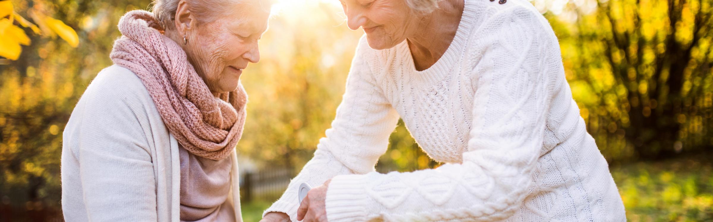 Een mantelzorger helpt een vrouw met haar krukken.