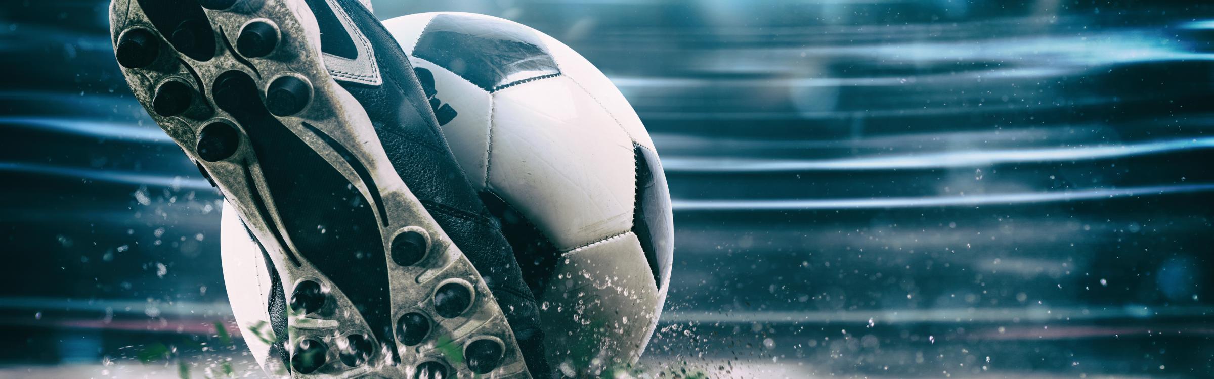 Iemand trapt tegen de voetbal die vooruit vliegt.