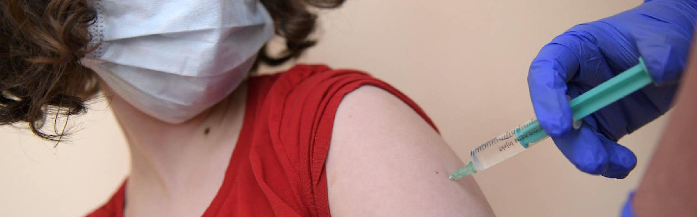 Een vrouw krijgt een coronavaccin toegediend.