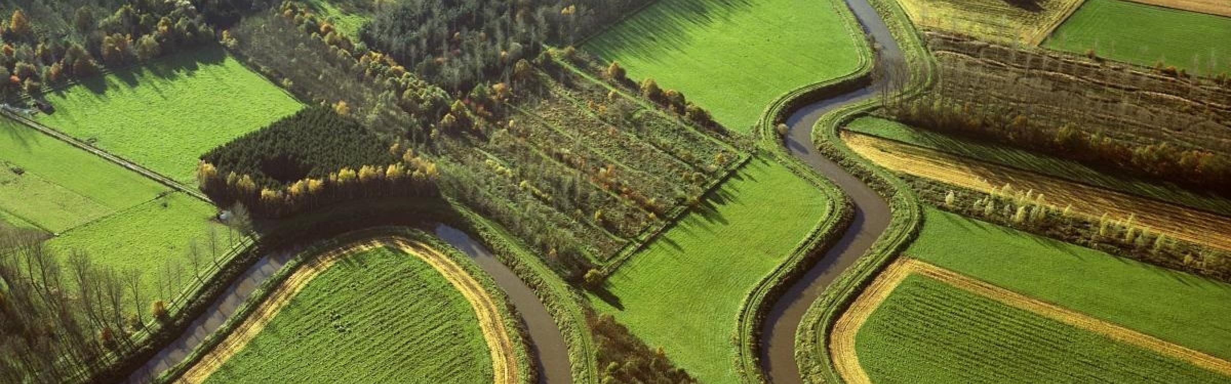 Een mooi natuurlandschap met een rivier al stromende door de weides en bomen.