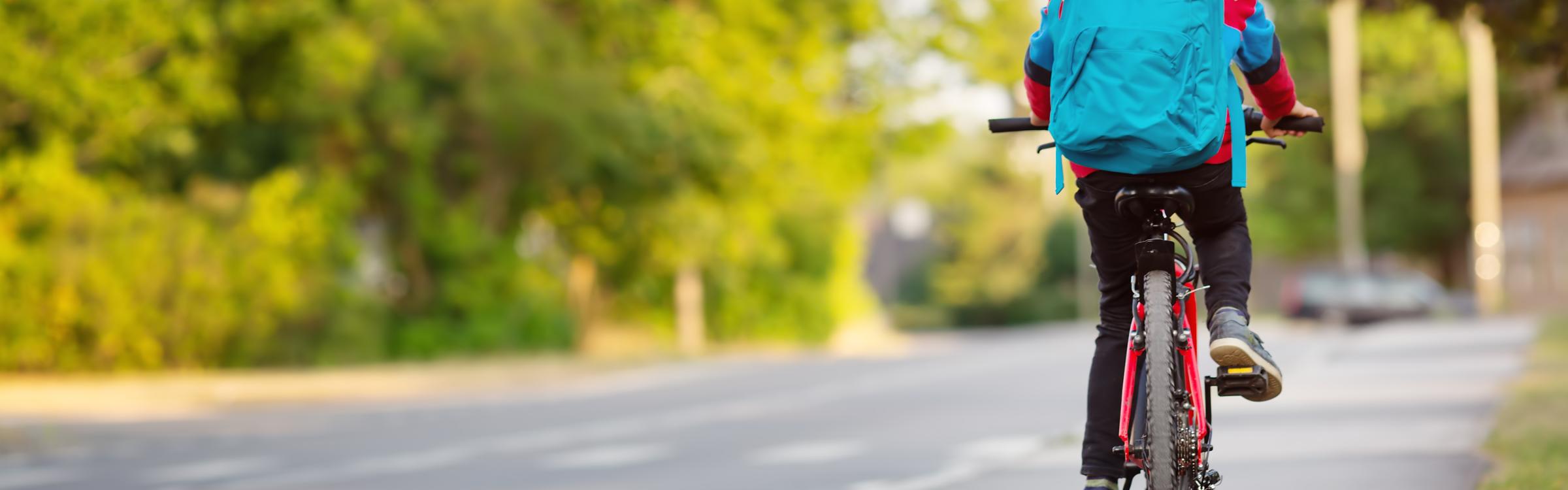Een jongetje met zijn fiets op weg naar school.