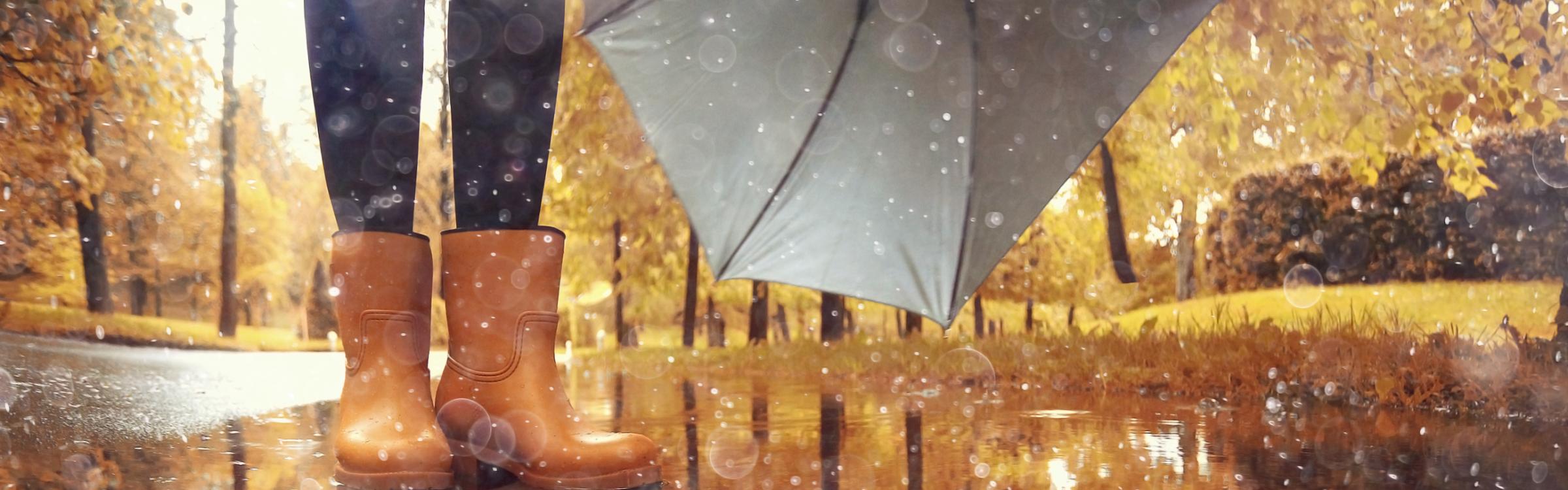Een vrouw staat in de regen met een paraplu in de hand.