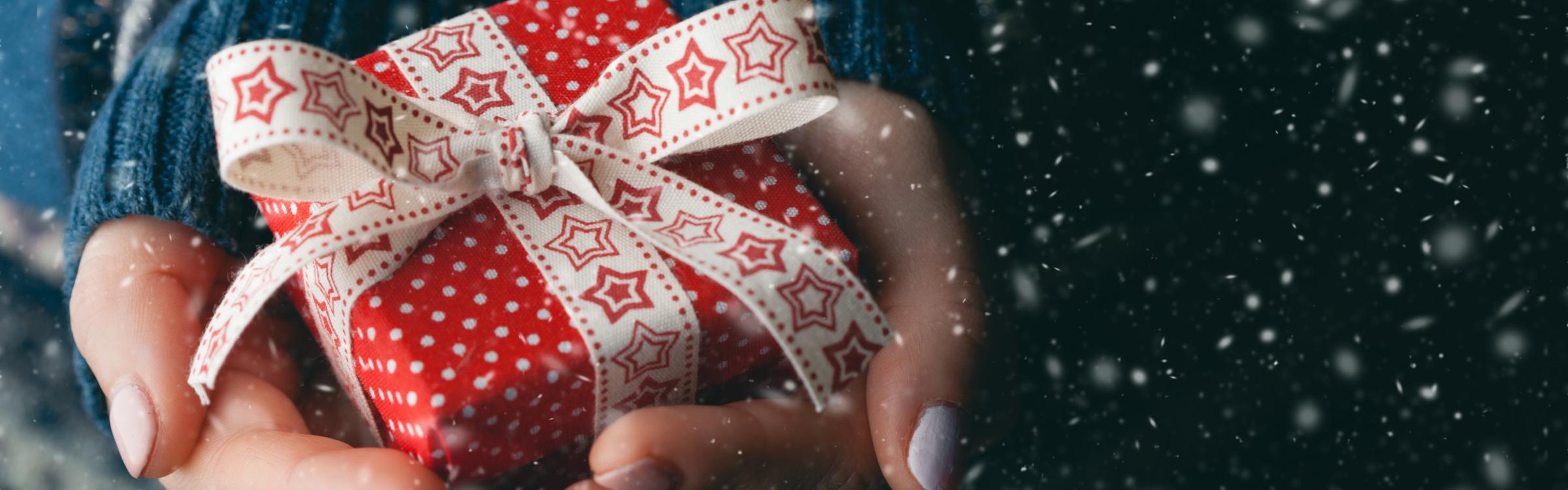 Iemand houdt een cadeautje vast voor Kerstmis.
