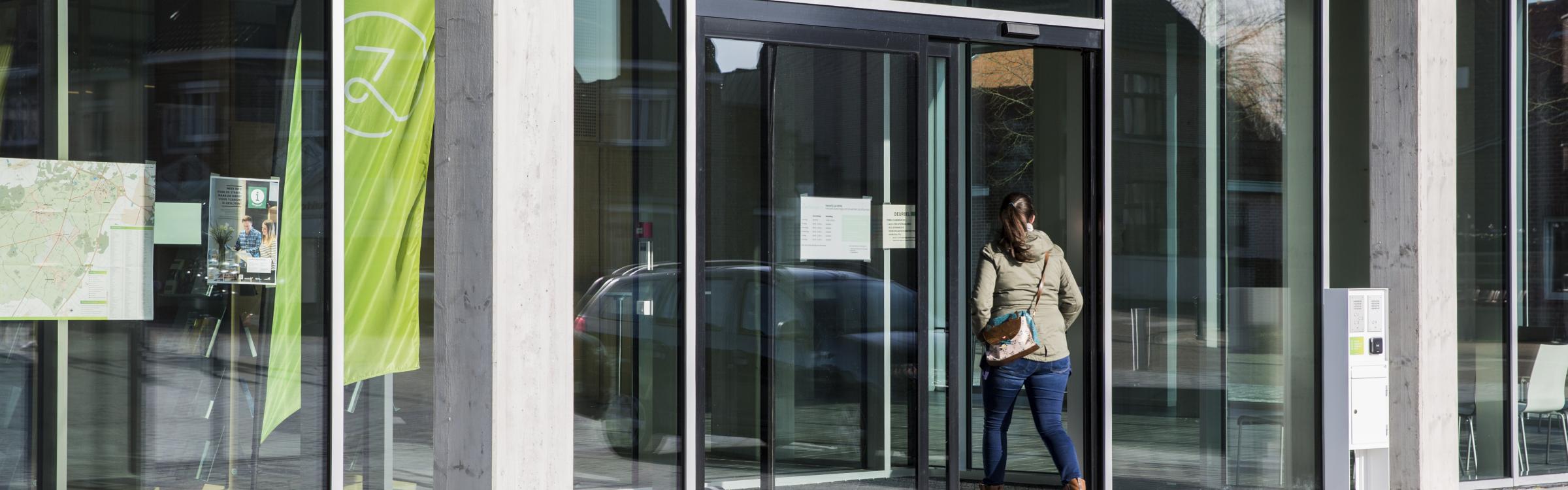 Een vrouw wandelt naar binnen in het gemeentehuis van Zedelgem.