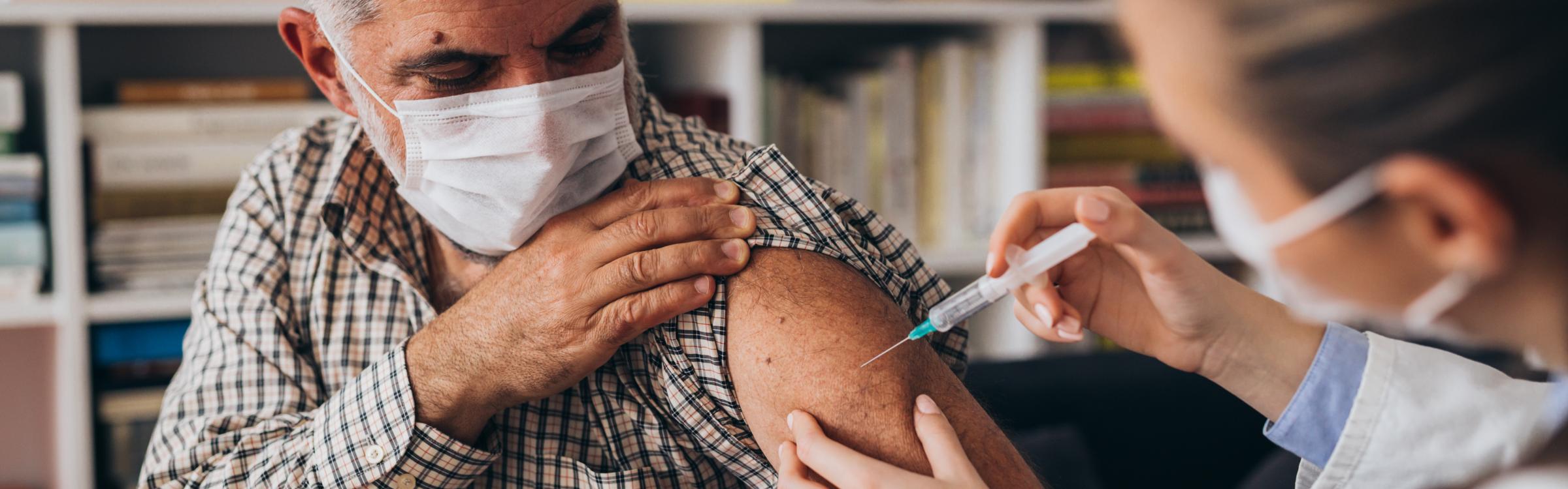 Een verpleegster dient iemand een vaccinatie toe.