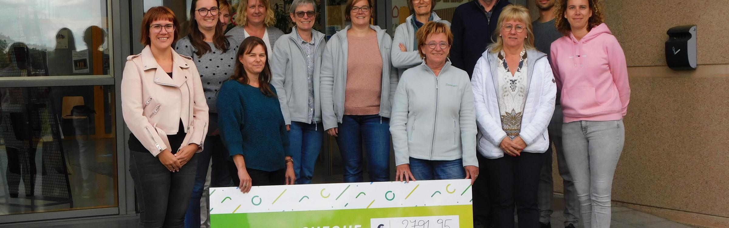 Lokaal bestuur en personeelsleden van de bibliotheek tonen de cheque voor Kom Op Tegen Kanker.