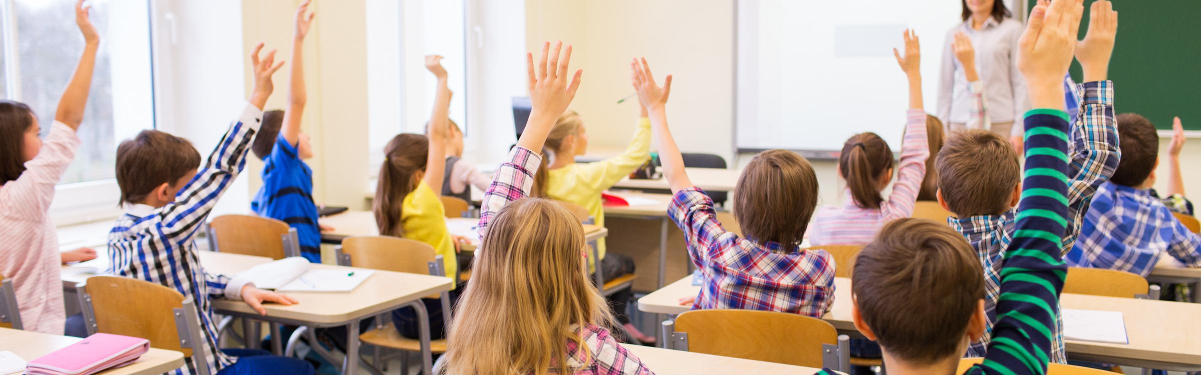 Leerlingen steken hun hand op tijdens de les om te antwoorden.