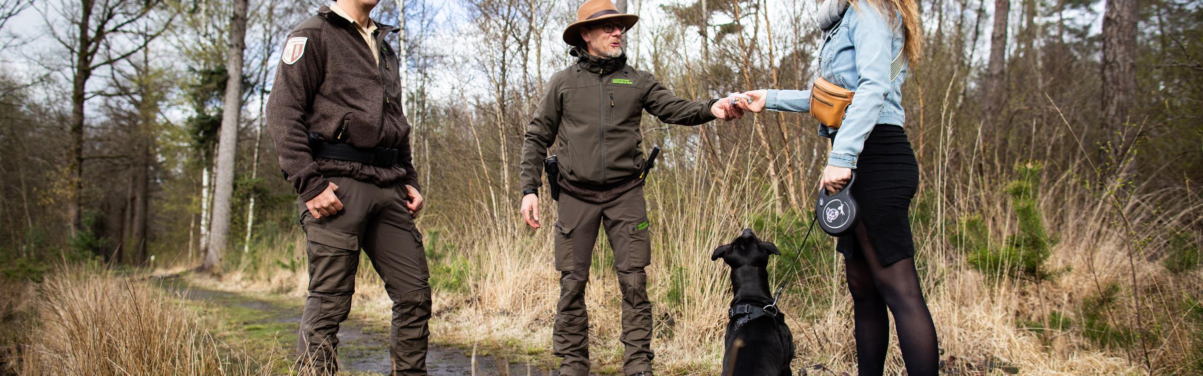 Boswachters in gesprek met wandelaar die op pad is met haar hond.