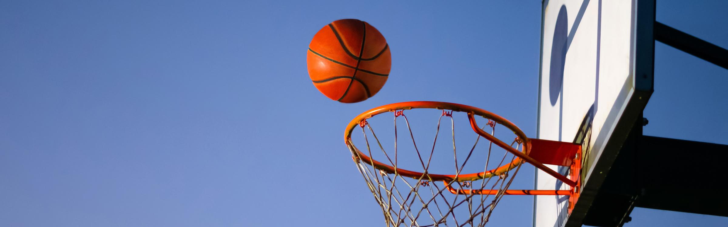 Basketbal valt bijna in de basketbalring op een zonnige dag.