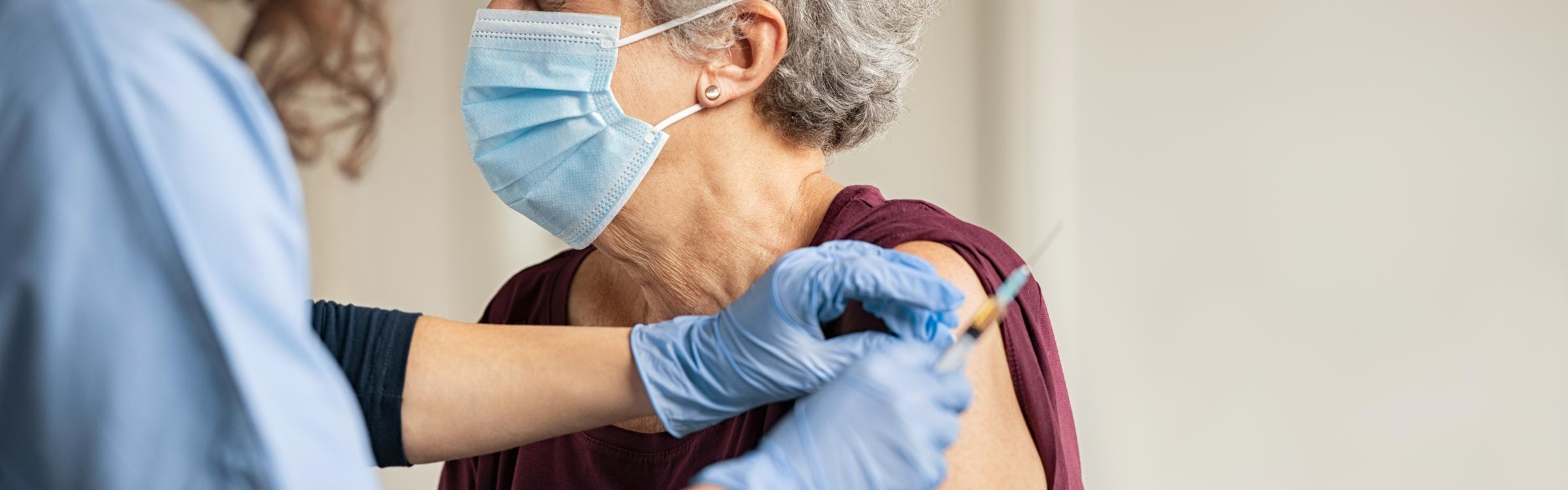 Verpleegster dient een vaccinatie toe aan een vrouw.