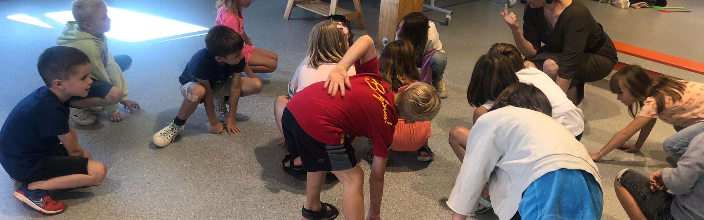 Kinderen doen bewegingsactiviteiten met een begeleider.