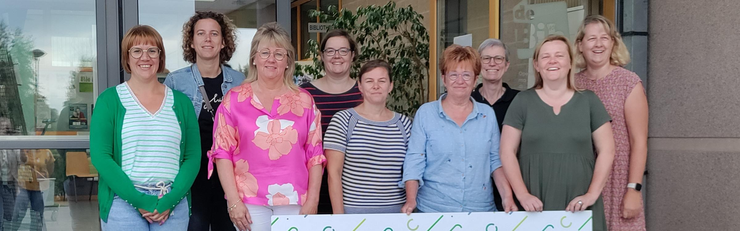 Lokaal bestuur en personeelsleden van de bibliotheek tonen de cheque voor Kom Op Tegen Kanker.