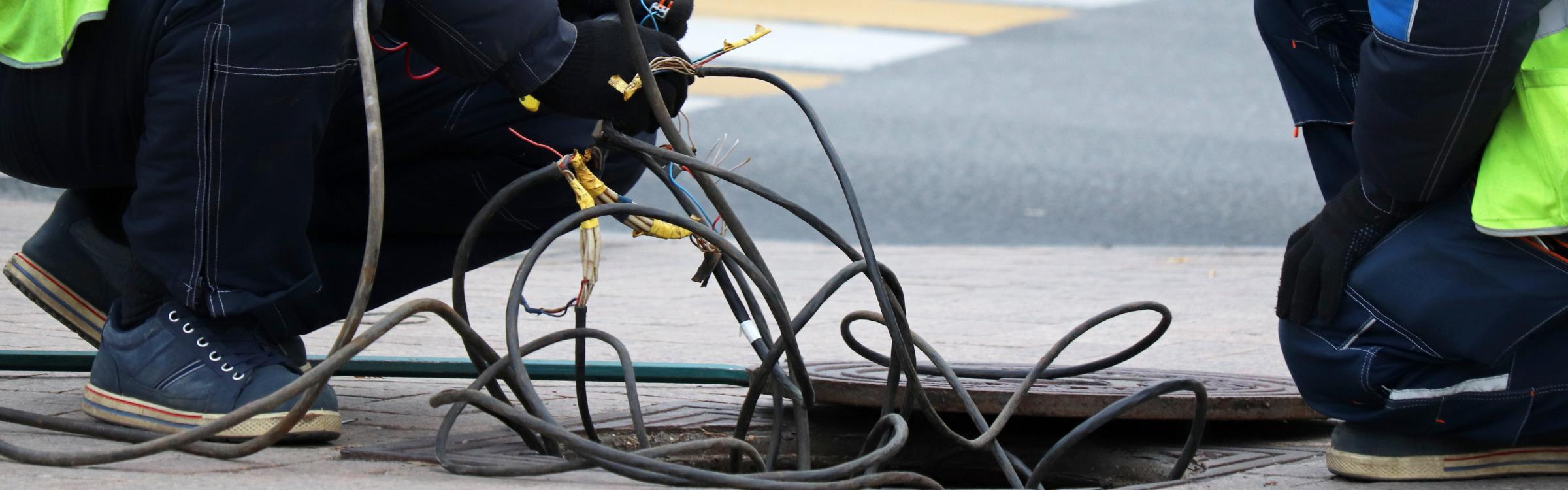 Werkmannen werken aan elektriciteit in de straat.