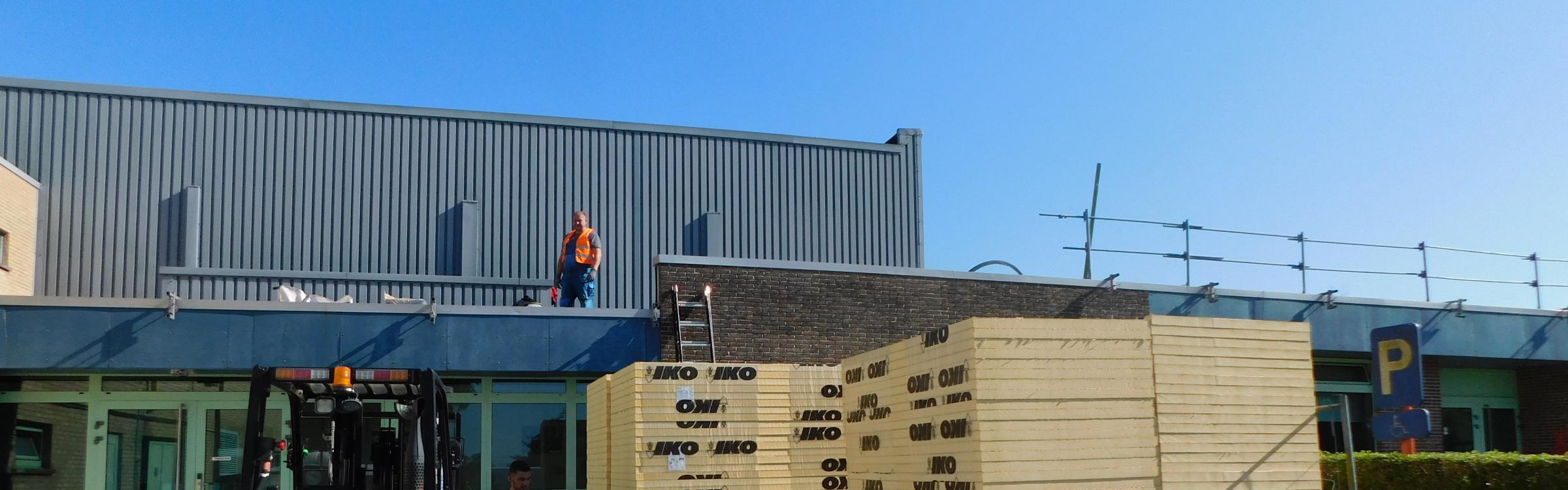 Werklieden op het dak van sportcentrum de Groene Meersen aan het werk.