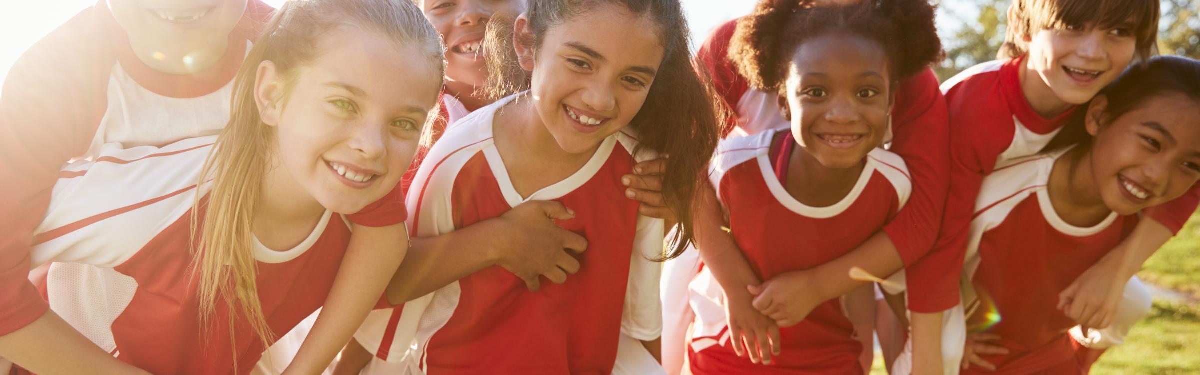 Voetballende kinderen knuffelen elkaar