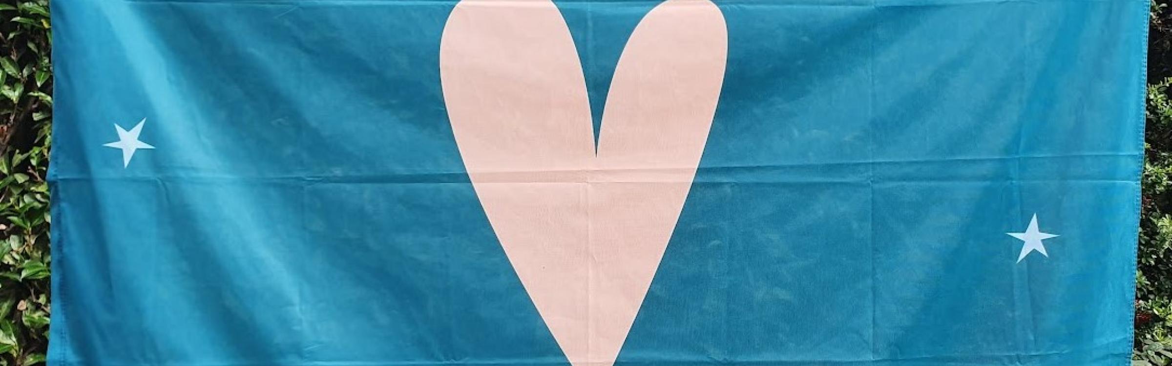 Vlag van de Koesterweek: donkergroene vlag met groot hart en sterretjes op