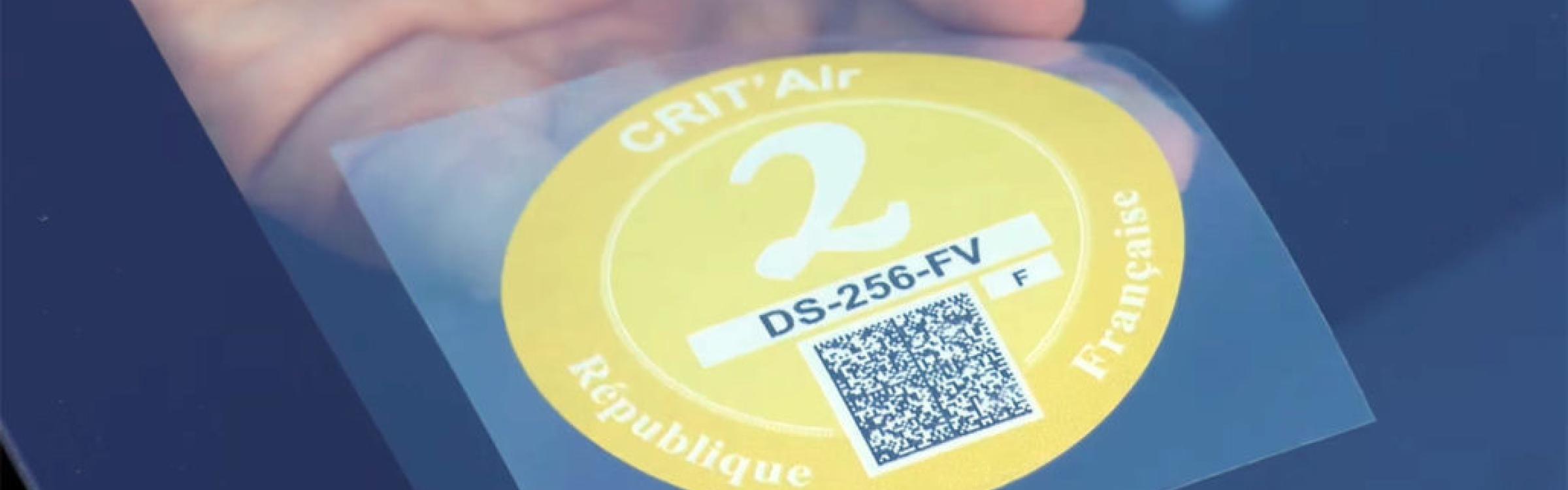 Persoon plakt een milieuvignet aan de ruit van auto