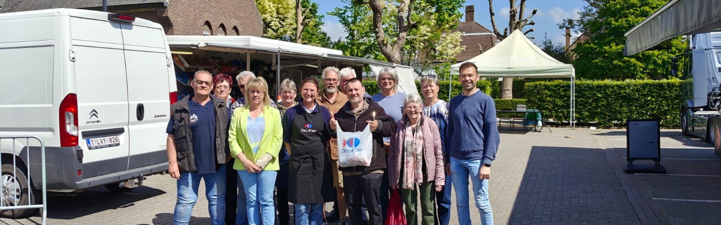 Groepsfoto van de prijsuitreiking van de Maand van de Markt tijdens de wekelijkse markt op het kerkplein van Zedelgem De Leeuw