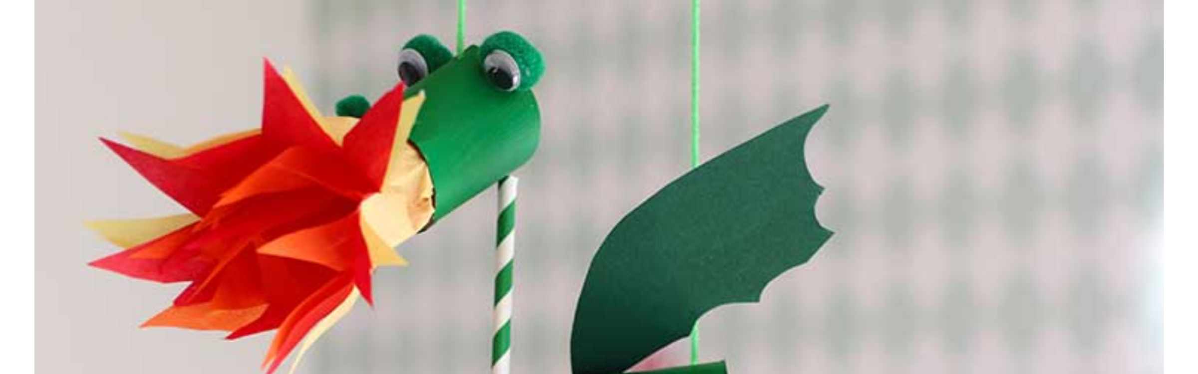 Knutselwerkje van een groene draak met vuur.