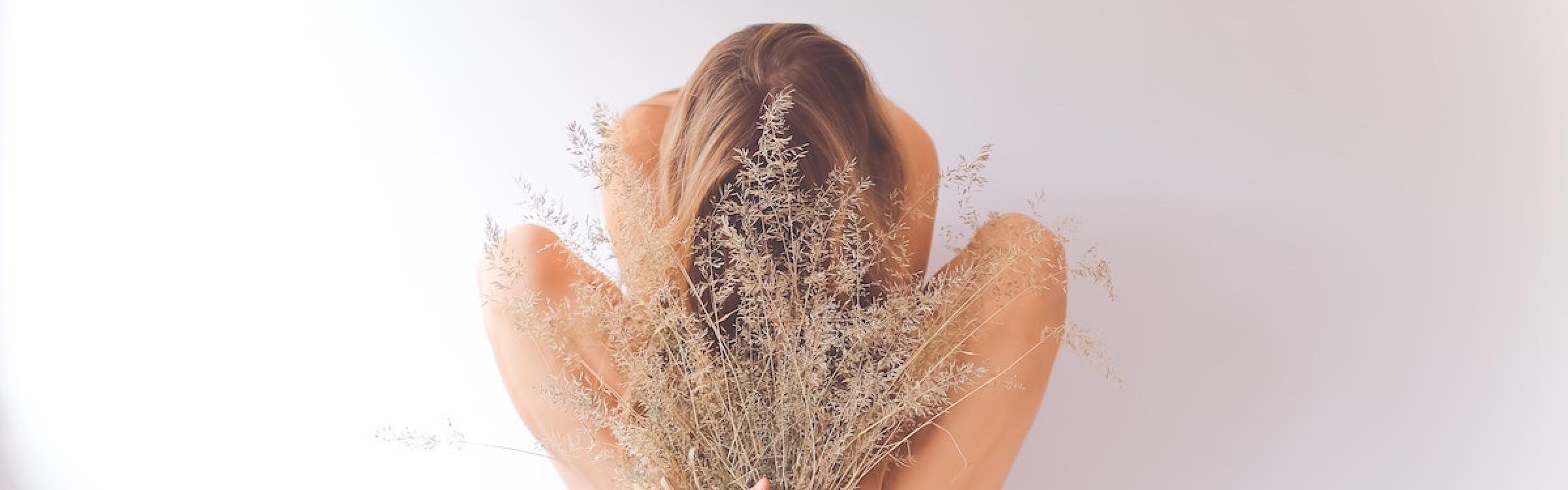 Vrouw zit op een krukje en houdt een bos gedroogde bloemen vast