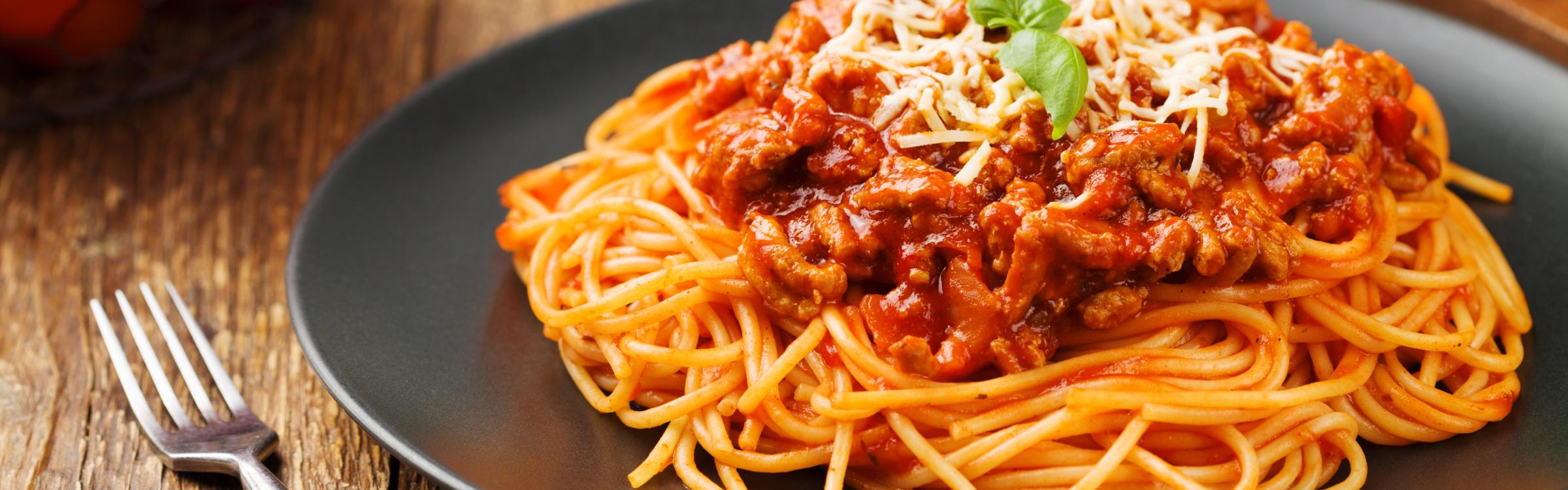Spaghetti op bord met tomaatjes en basilicum ernaast