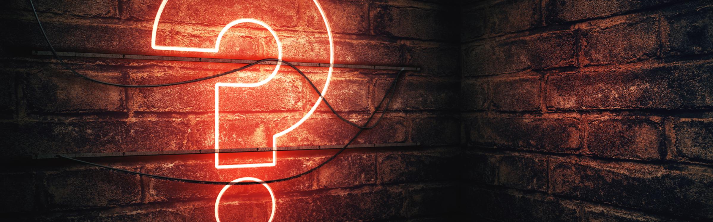 Neon licht in de vorm van een vraagteken aan een muur