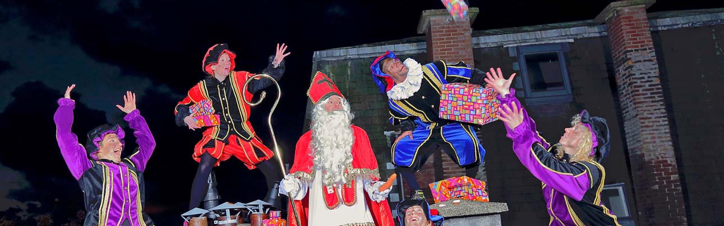 Foto van Sinterklaas 5 Pieten op een dak. 