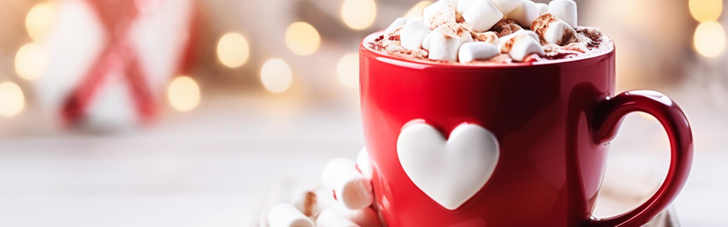 Warme chocomelk met marshmellows in een rode tas met een wit hartje op