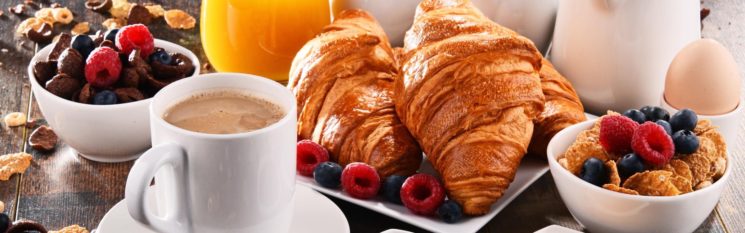 Uitgestald ontbijt met croissants, koffie, fruit, eitje, fruitsap...