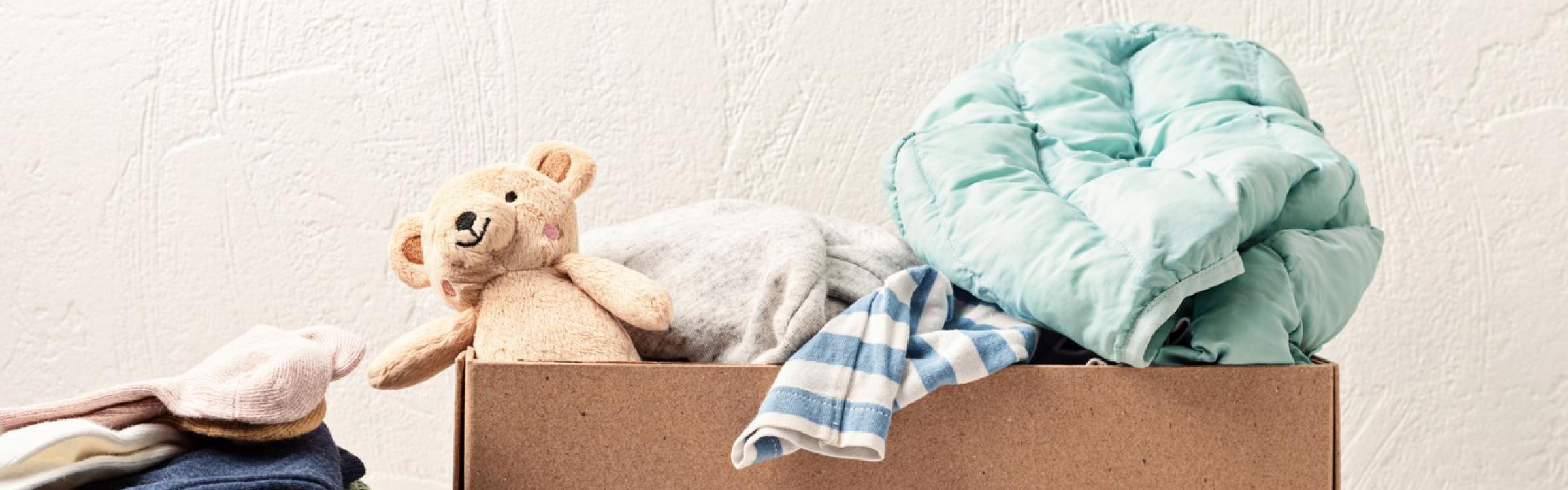 Doos met tweedehandskledij en een knuffelbeer