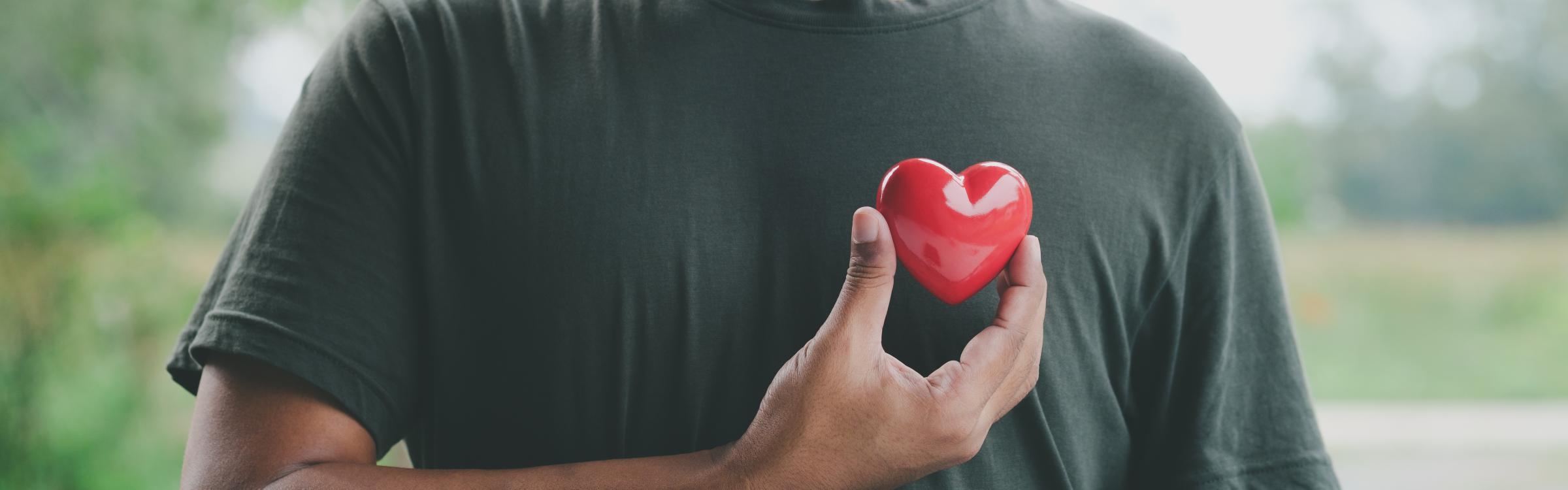 Man houdt een plastic hartje voor zijn borst