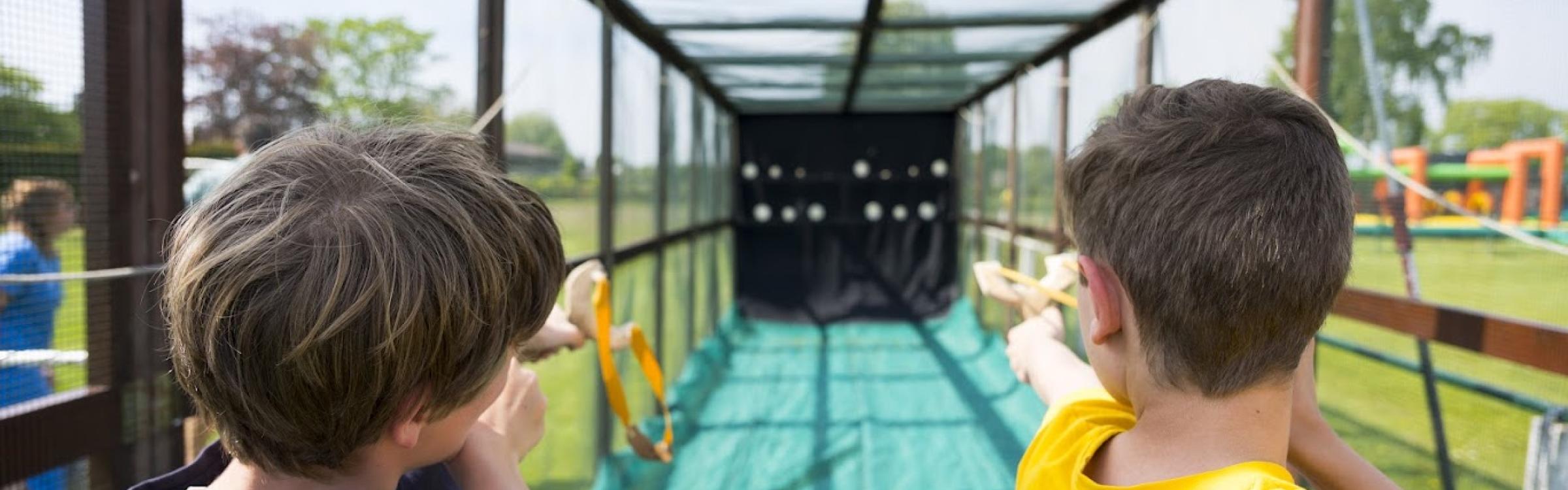 2 jongens schieten met katapulten naar een doel