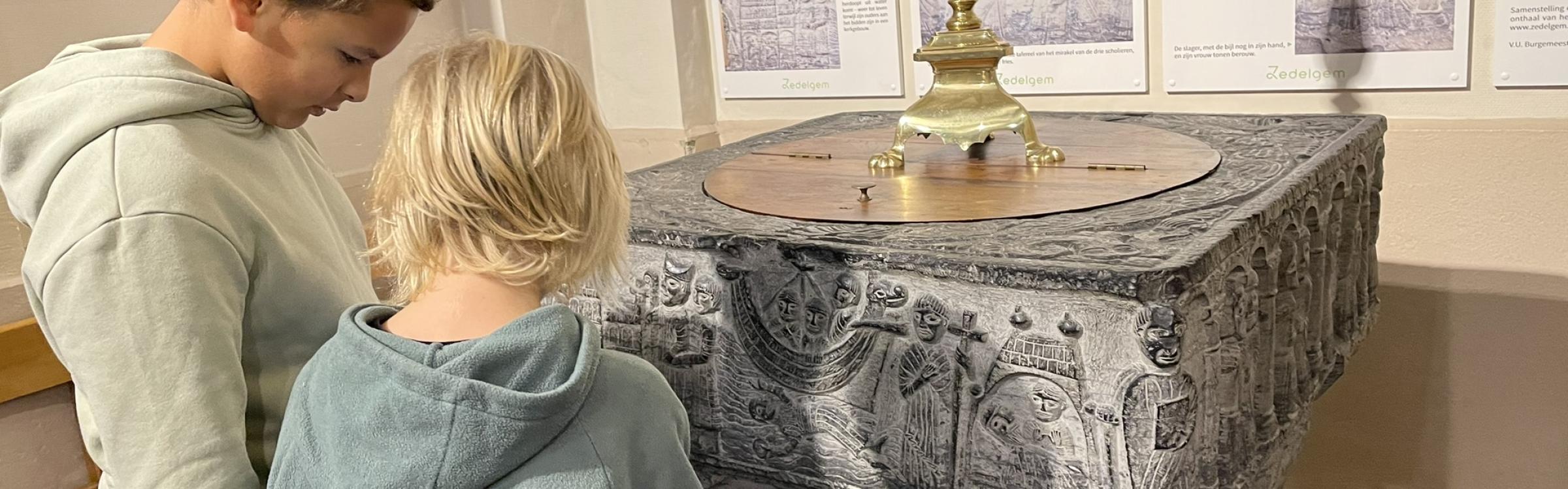 2 kinderen staan aan de doopvont in de Sint-Laurentiuskerk in Zedelgem